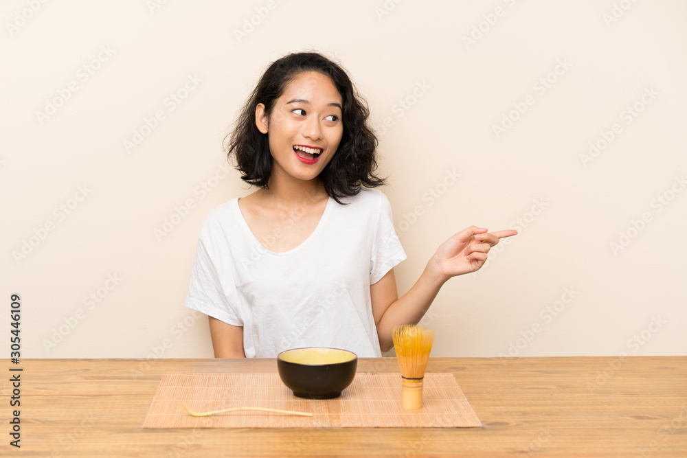 Young asian girl with tea matcha surprised and pointing finger to the side Young asian girl with tea matcha surprised and pointing finger to the side