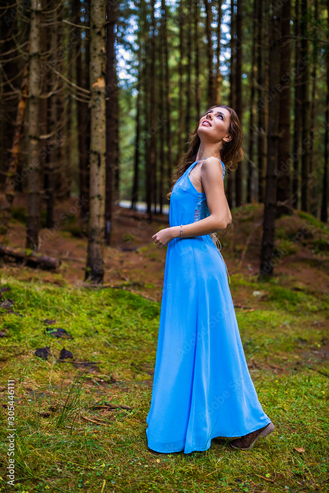 Beautiful woman in blue dress in the forest in autumn day