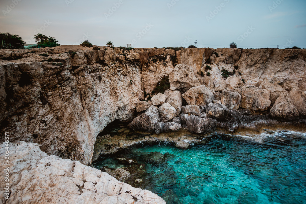 A blue lagoon in Cape Greco, Cyprus. The water has many shades of blue. Crystal clear water. Sharp rocks emerging from the sea. Calm surface of the sea. Bright and sunny day.