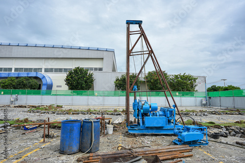 Construction workers assembly rig and machine for soil investigation works at construction site.