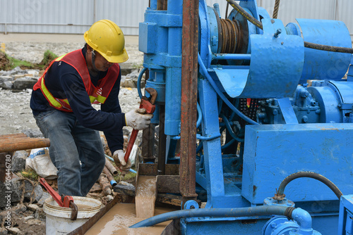 Construction workers drilling obtaining soil samples field for geological logging, analysis and testing, soil investigation before design pile tip for construction site.