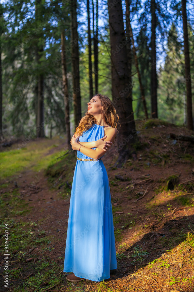 Beautiful woman in blue dress in the forest in autumn day