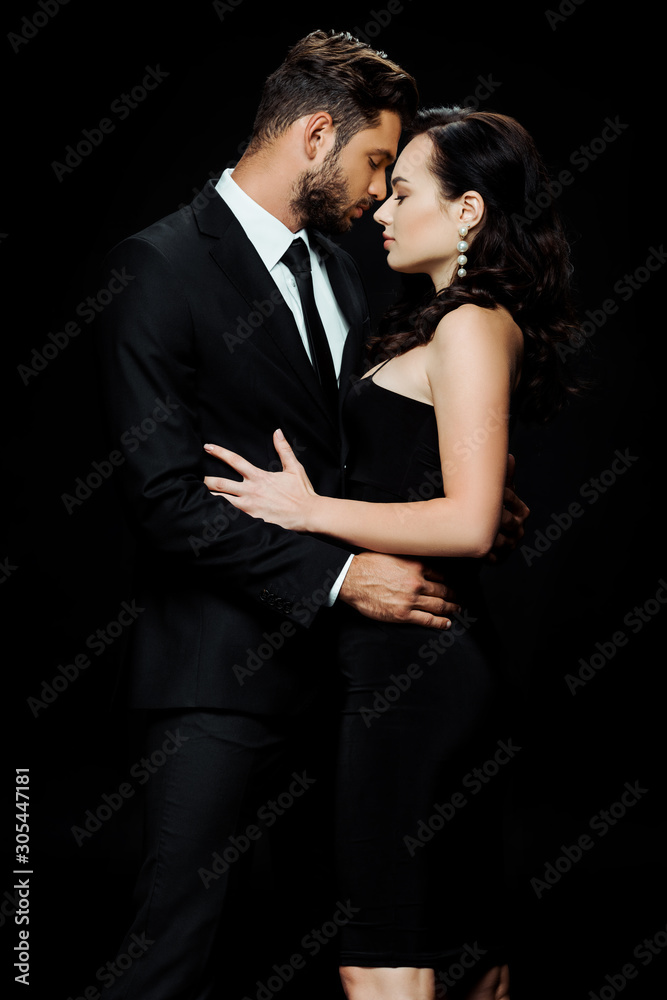 side view of handsome bearded man with closed eyes standing with attractive girl isolated on black side view of handsome bearded man with closed eyes standing with attractive girl isolated on black
