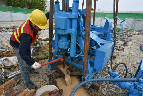 Construction workers drilling obtaining soil samples field for geological logging, analysis and testing, soil investigation before design pile tip for construction site.