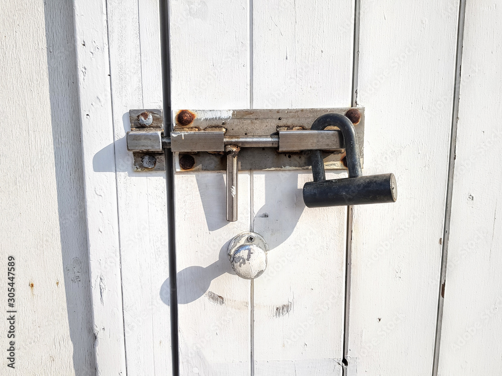 White wooden close door locked by deadbolt. Wood porch of the house from stained white boards White wooden close door locked by deadbolt. Wood porch of the house from stained white boards