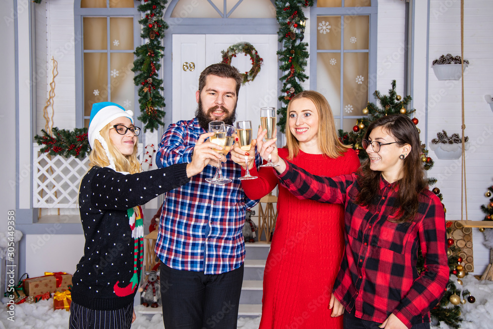 Naklejka premium Christmas company with glasses of champagne three girls and bearded man portrait candid people in decorated room interior environment background, smiling and happy emotions in winter holidays time 