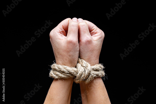 Woman with tied hands. Hands tied with rope on dark background. International Day for the Elimination of Slavery.