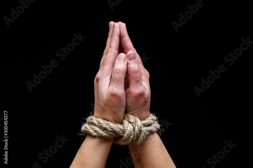 Woman with tied hands. Hands tied with rope on dark background. International Day for the Elimination of Slavery.