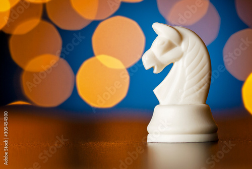 White horse chess piece over a colorful bokeh