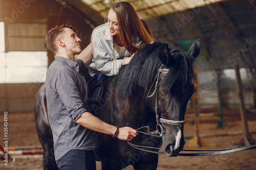 Fototapeta Naklejka Na Ścianę i Meble -  Couple on a ranch. Pair standing with a horse. Girl with her boyfriend