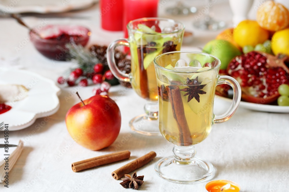 christmas hot cider. hot winter drink Cranberry Apple Cider Punch. Garnish with apples, oranges, and cranberries. hot apple cider with spices on a festive table on Christmas or New Year. christmas hot cider. hot winter drink Cranberry Apple Cider Punch. Garnish with apples, oranges, and cranberries. hot apple cider with spices on a festive table on Christmas or New Year.