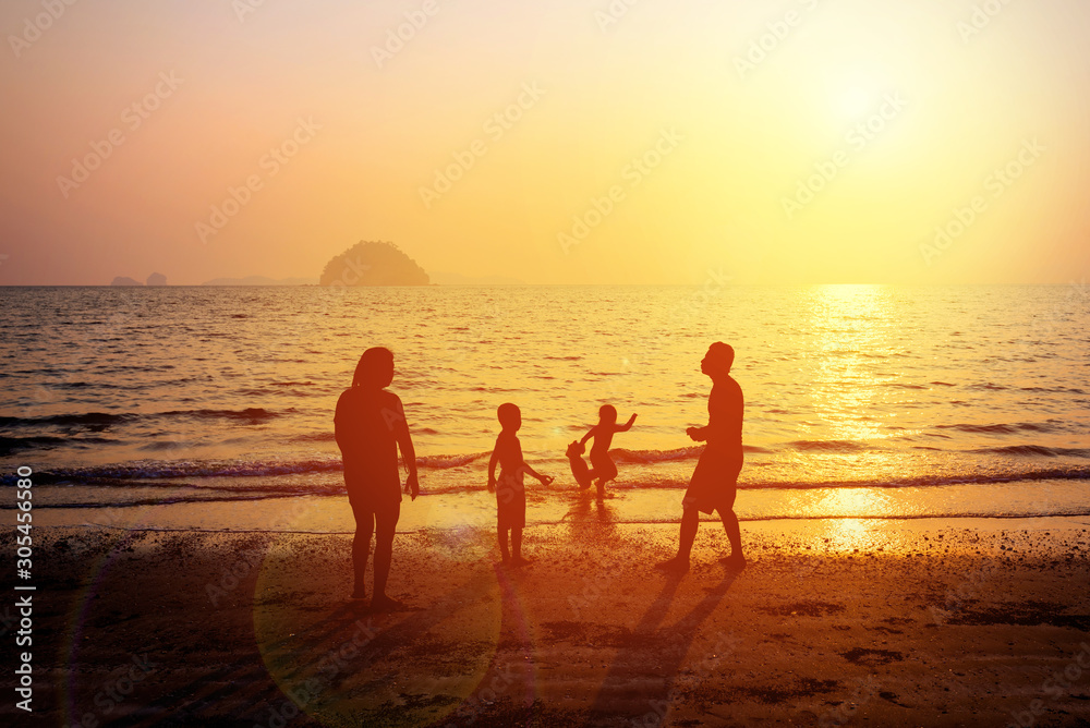 Silhouette of happy family of four people, mother, father, daughter and son enjoy at sunset beach. Dad, mom and children playing on the beach. Concept of friendship forever and  summer vacation time.