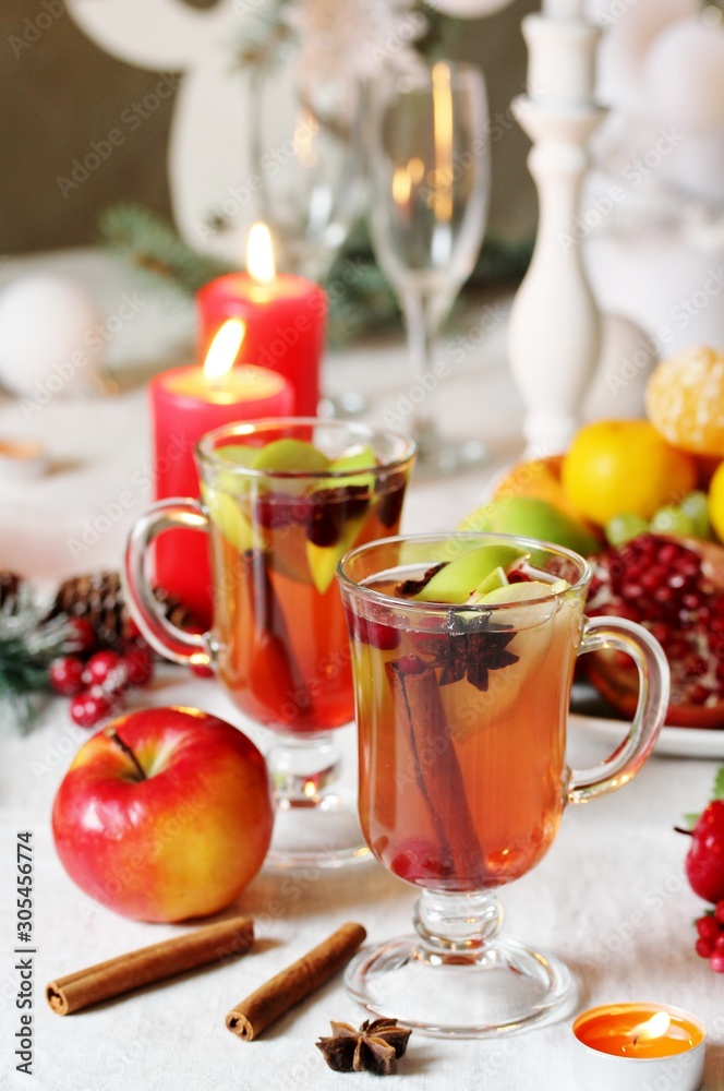 hot winter drink Cranberry Apple Cider Punch. Garnish with apples, oranges, and cranberries. hot apple cider with spices on a festive table on Christmas or New Year. hot winter drink Cranberry Apple Cider Punch. Garnish with apples, oranges, and cranberries. hot apple cider with spices on a festive table on Christmas or New Year.