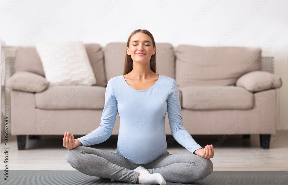 Pretty pregnant woman meditating in lotus pose