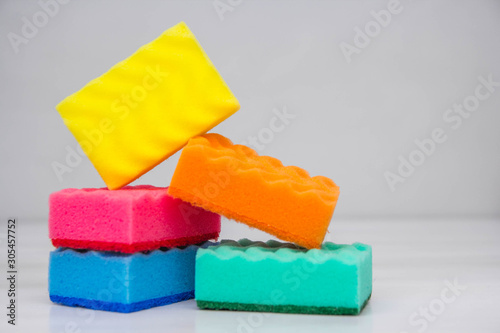 Multicolored sponges for cleaning and washing dishes on a white table. Space for text