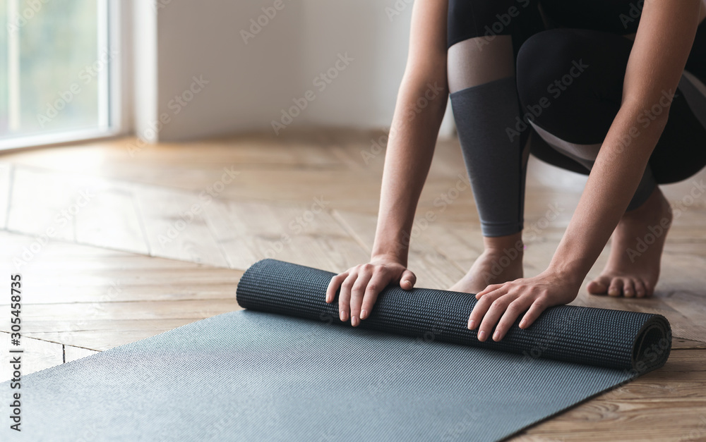 Cropped photo of girl rolling sport mat at studio