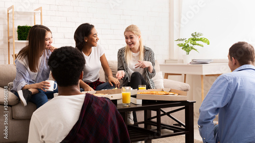 Teen friends chatting at home and eating pizza