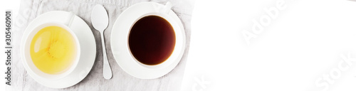Two cups of black and green tea with cane and white sugar cubes on white. Top view. Half banner format. Wide panoramic image.