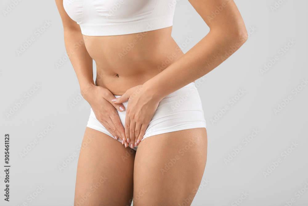 Young woman suffering from abdominal pain on grey background. Gynecology concept - obrazy, fototapety, plakaty 