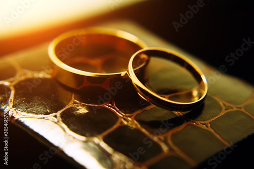 Gold rings of the newlyweds shine and reflect the light, close-up, blurred background. Abstract photo, wedding accessories.