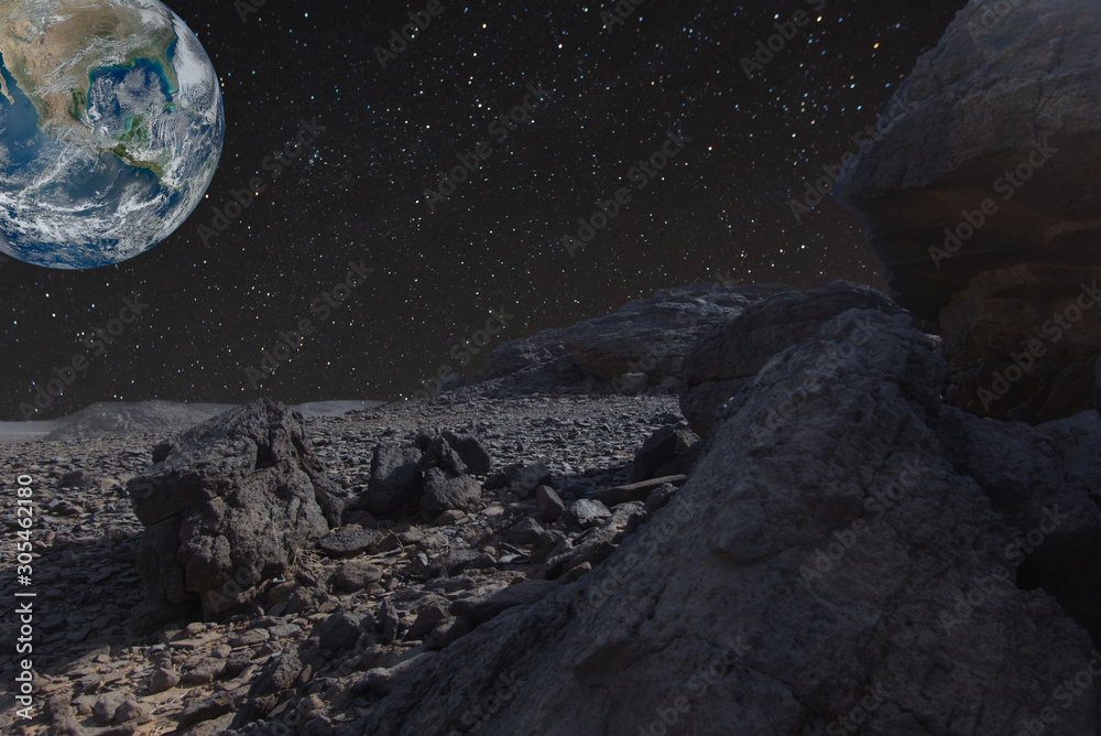 Obraz premium Surreal composite image of the stone desert in Sudan with a starry sky and planet Earth in the background. Elements of this image furnished by NASA