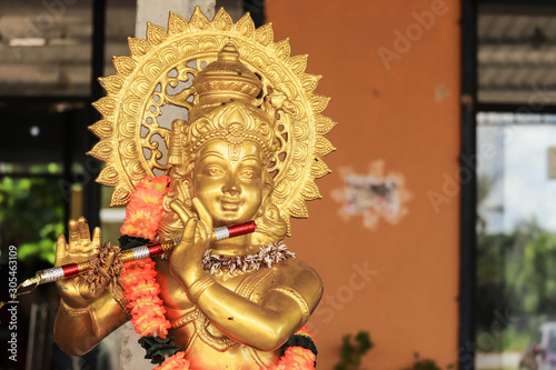 Golden Color Statue Of Lord God Idol Playing Flute With Flower Garland