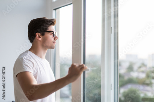 Young man opens the window. Ventilating a house in hot weather.