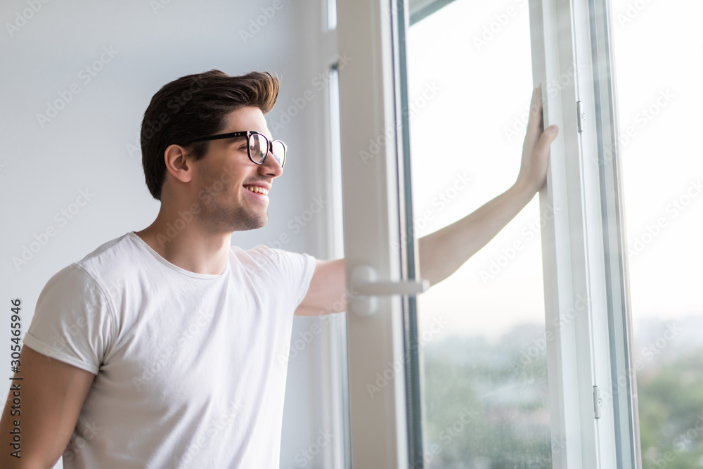 Young man opens the window. Ventilating a house in hot weather. Young man opens the window. Ventilating a house in hot weather.