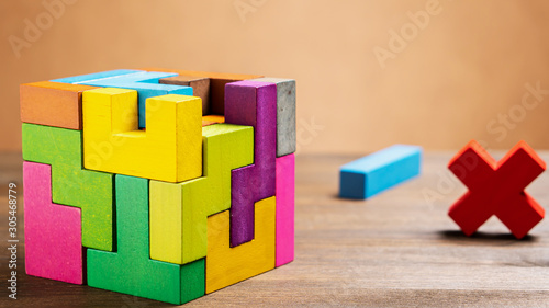 Missed items are seting in the colorful wooden cube puzzle on the brown table. Geometric shapes on a wooden background.