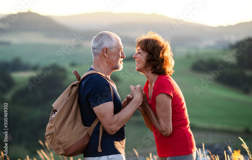 Senior tourist couple hikers with backpack standing in nature, resting.