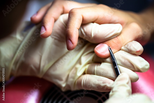 Manicure. The device removes the cuticle. Moving aside cuticle from the surface of the nail