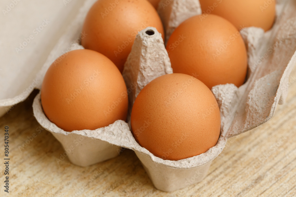 Brown chicken eggs in carton box on wooden table Brown chicken eggs in carton box on wooden table