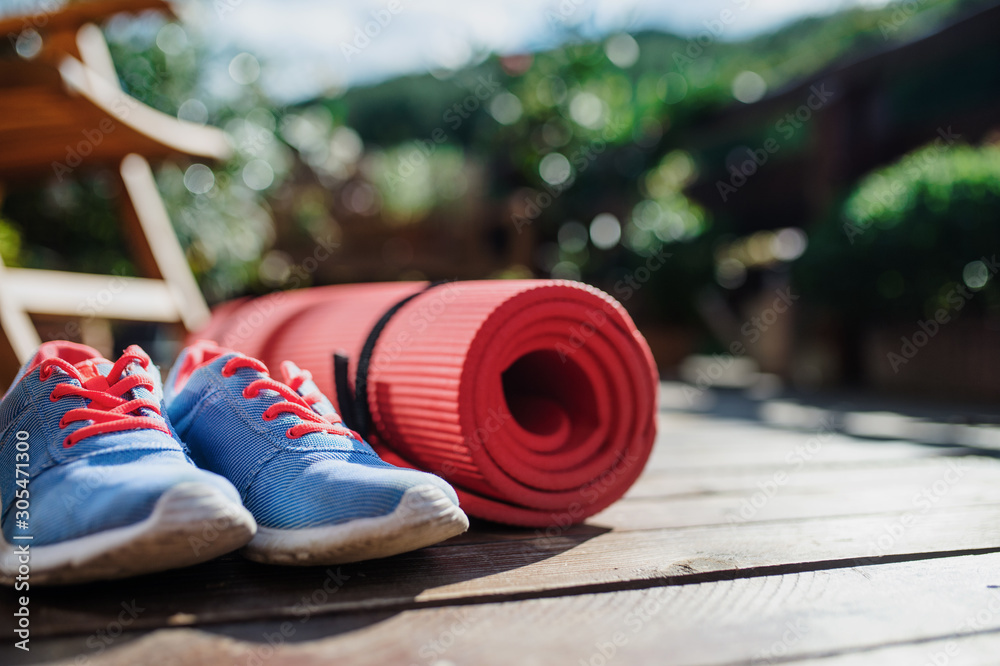 Exercise mat and trainers outdoors on a terrace in summer. - obrazy, fototapety, plakaty 