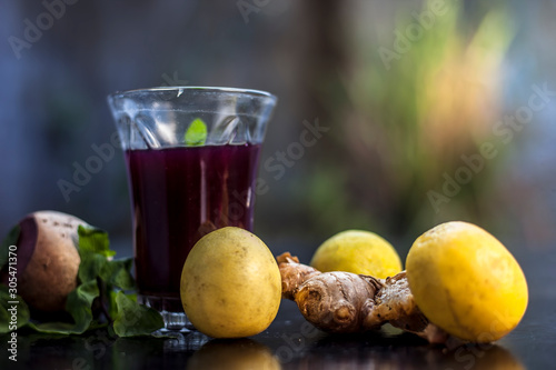 Beetroot juice with some mint leaves lemon juice and ginger in it on black glossy surface in a glass for weight loss. Horizontal shot with bokeh background. photo