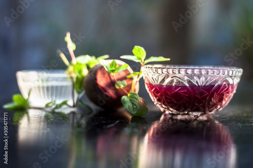 Home remedy for dandruff on wooden surface i.e., beetroot stock well mixed with water in a glass bowl along with some freshwater and raw sliced beetroot. Horizontal shot with blurred creamy bokeh. photo