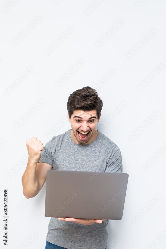 Emotional young man with laptop celebrating victory on white background Emotional young man with laptop celebrating victory on white background