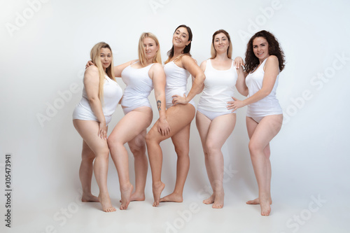 In love with myself. Portrait of beautiful plus size young women posing on white background. Happy smiling female models looks confident. Concept of body positive, beauty, fashion, style, feminism.