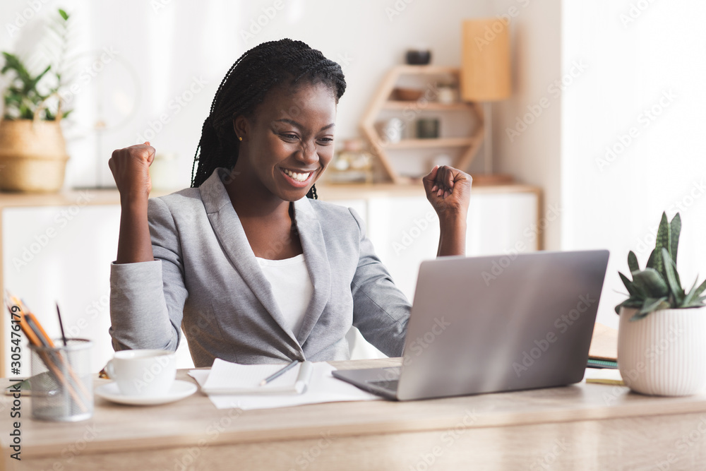 Excited Afro Businesswoman Celebrating Success At Workplace In Modern Office Excited Afro Businesswoman Celebrating Success At Workplace In Modern Office