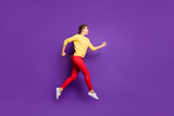 Full length profile photo of funny millennial lady jumping high rushing sale shopping speed running wear casual yellow pullover red trousers isolated purple color background