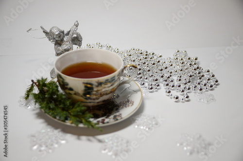 Merry Cristmas. New Year. On a white background is a cup of tea, decorative shiny silver beads.