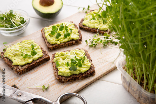 Whole grain toasts with avocado spread and microgreen sprouts