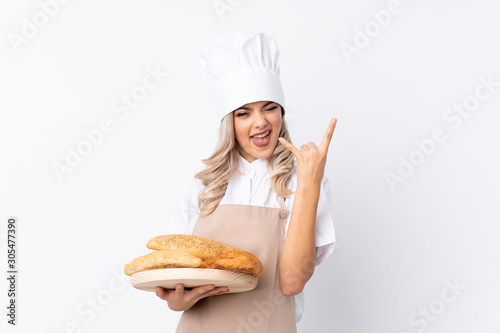 Teenager girl in chef uniform. Female baker holding a table with several breads over isolated white background unhappy and frustrated with something