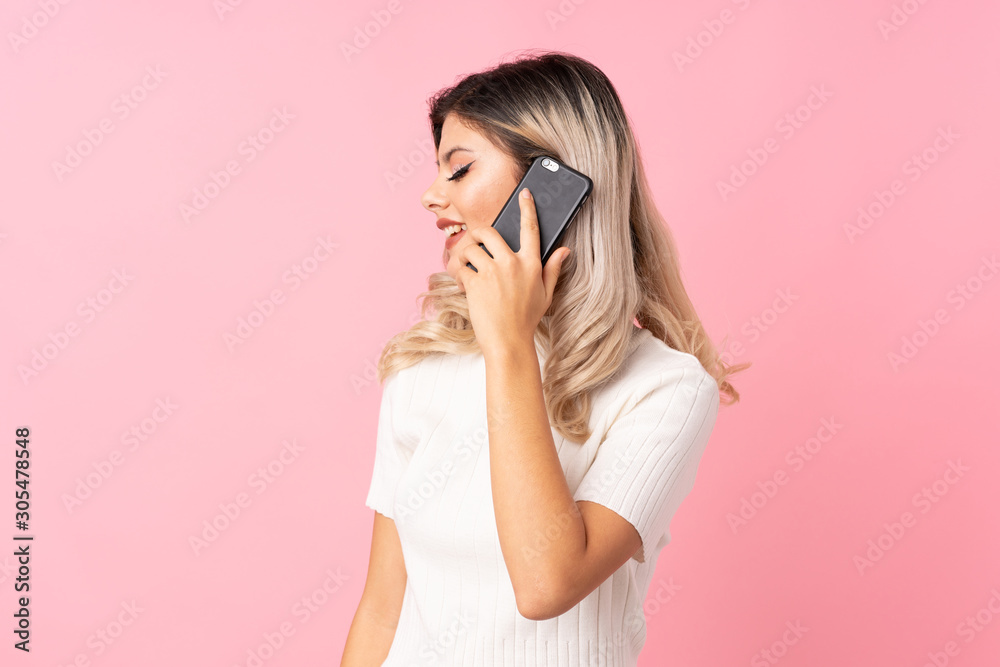Teenager girl over isolated pink background keeping a conversation with the mobile phone with someone Teenager girl over isolated pink background keeping a conversation with the mobile phone with someone