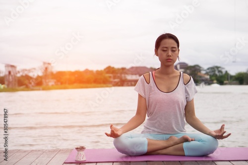 Young healthy woman practice yoga in the morning with the lake as background. Concept of healthy.