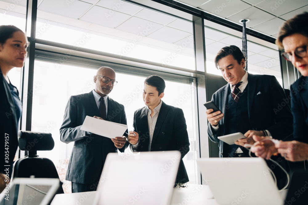 Business colleagues planning while standing in board room at workplace Business colleagues planning while standing in board room at workplace