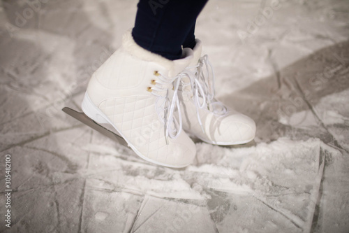 women's white figure skates on the rink.