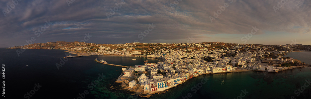 Aerial drone panoramic photo of picturesque old port in main village of Mykonos island at sunset and iconic church of Paraportiani with beautiful colours, Cyclades, Greece