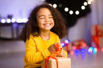 Happy african girl unwrapping her xmas gifts at home