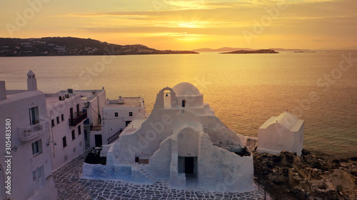 Aerial drone panoramic view of landmark church of Paraportiani overlooking the Aegean sea in main village of Mykonos island at sunset with beautiful colours, Cyclades, Greece photo