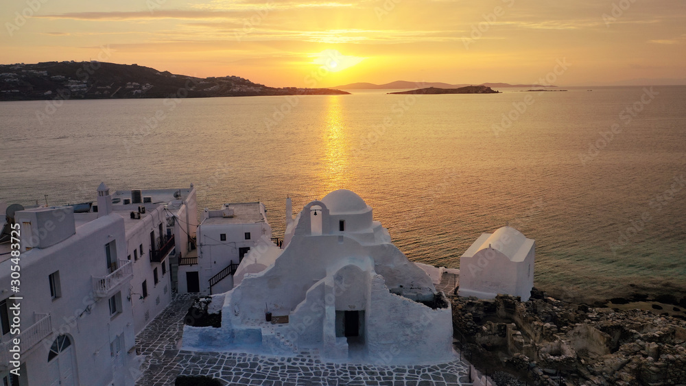 Aerial drone panoramic view of landmark church of Paraportiani overlooking the Aegean sea in main village of Mykonos island at sunset with beautiful colours, Cyclades, Greece